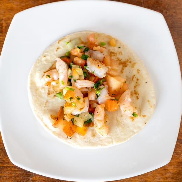 A shrimp taco from Taqueria Taxco, topped with diced tomatoes, onions, and cilantro.