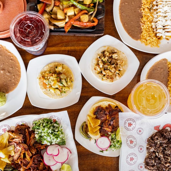 Overhead view of a wooden table laden with various Mexican dishes, including tacos, fajitas, and drinks.