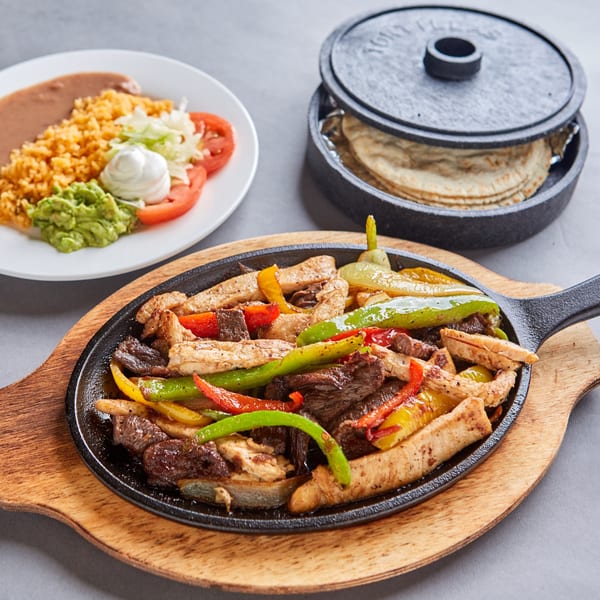 Sizzling chicken and beef fajitas with colorful bell peppers, served with rice, beans, and tortillas.